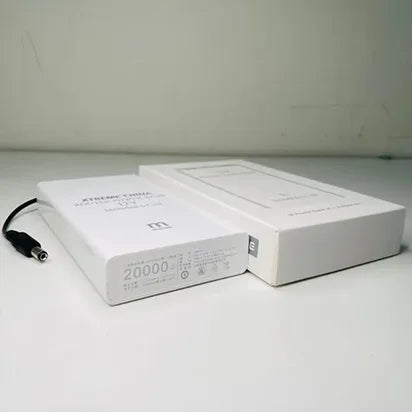 White power bank with cable and packaging on a light gray surface